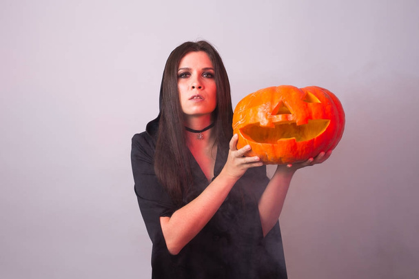 Halloween boszorkány gazdaság egy narancssárga sütőtök Jack o Lantern füst - Fotó, kép