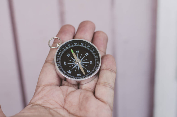 hand holding compass over wooden wall - Photo, Image