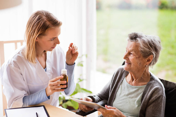 Health visitor and a senior woman with tablet. - Zdjęcie, obraz