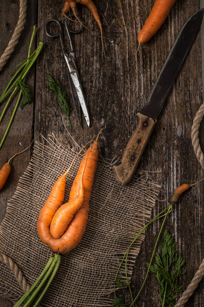 Unusual carrots on an old wooden table - Zdjęcie, obraz
