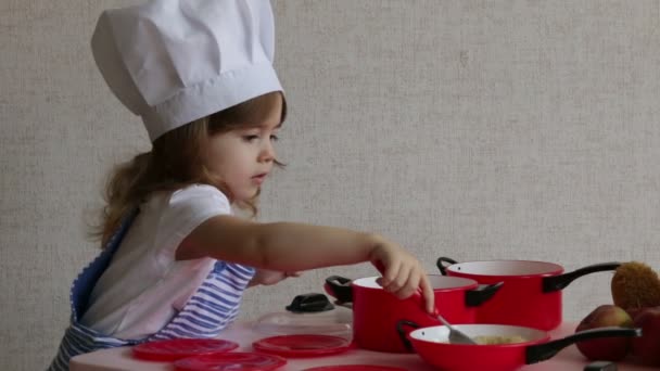 Retrato linda niña vestida como un chef cocina comida
 - Imágenes, Vídeo