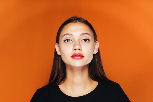 cute girl with big lips looking at the camera. Isolated on an orange background - Фото, изображение