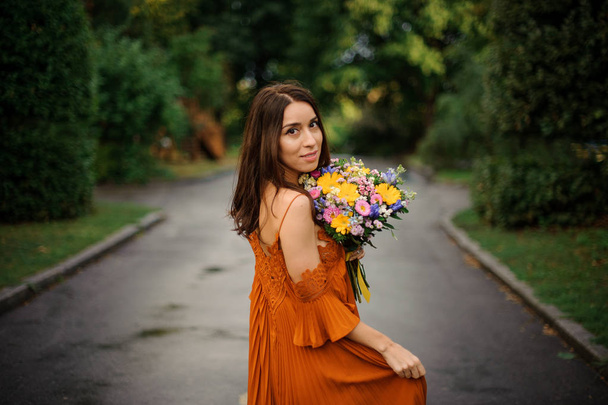 Portrait of young and beautiful woman in long orange dress - Photo, Image
