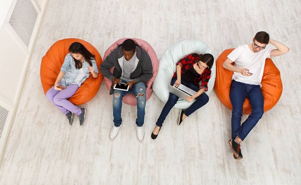 Friends using gadgets, sitting indoors in line - Фото, зображення