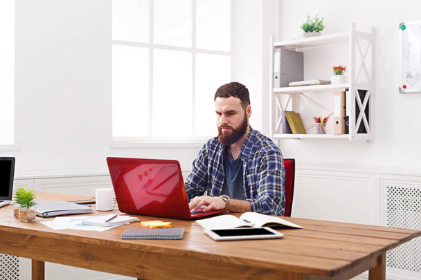 Hombre de negocios serio que trabaja con el ordenador portátil en la oficina blanca moderna
 - Foto, imagen
