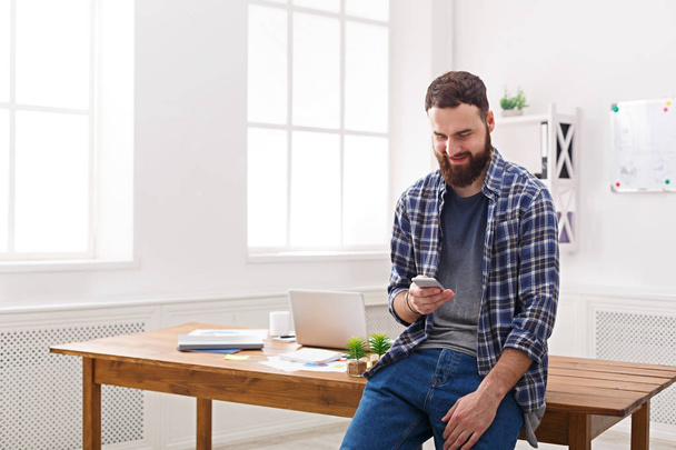 Relaxed young businessman using mobile in office - Foto, Imagem
