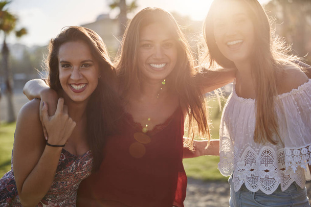 Três meninas felizes de pé juntos na luz do sol sorrindo
 - Foto, Imagem