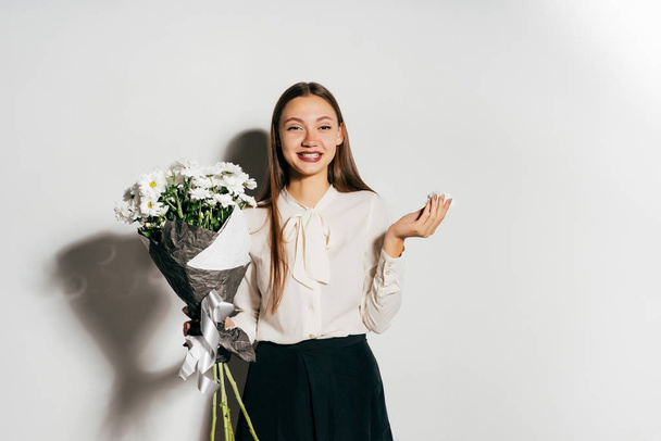 happy girl in blouse holding a bouquet of beautiful white flowers and looking directly at the camera, isolated on a white background. Happy birthday, fun. - Photo, Image