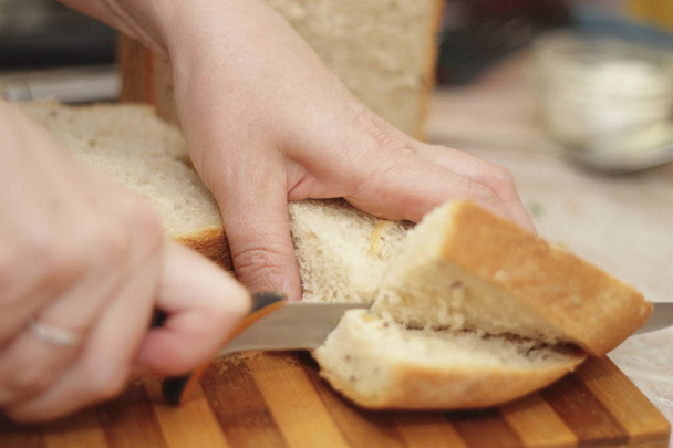 Woman cutting a bread on the wooden desk - Foto, immagini