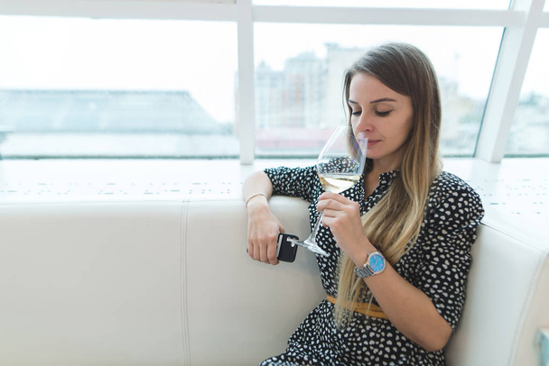 Retrato de una mujer hermosa y elegante que huele el aroma del vino blanco en un restaurante elegante. Descanso en el restaurante
. - Foto, imagen