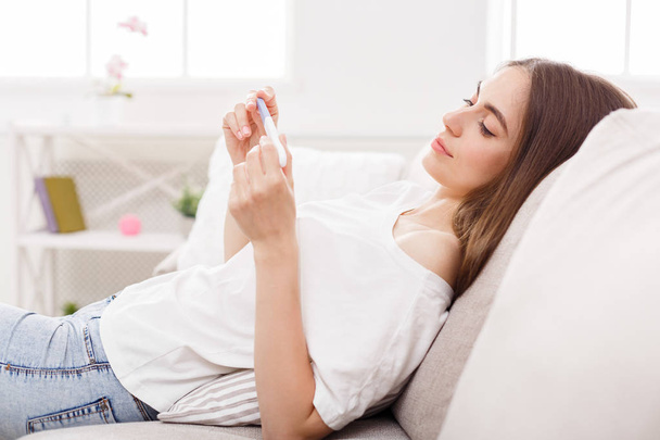 Chica feliz soñando con el niño con la prueba de embarazo en casa
 - Foto, imagen