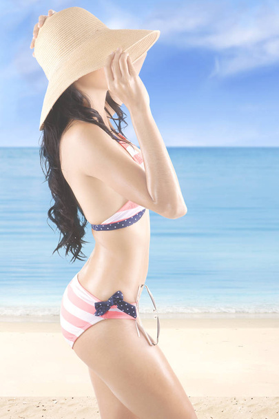Молодая женщина в полосатых купальниках на берегу
 - Фото, изображение
