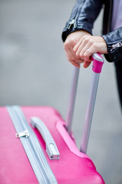 Pink suitcase close-up with hand girl on handle - Φωτογραφία, εικόνα