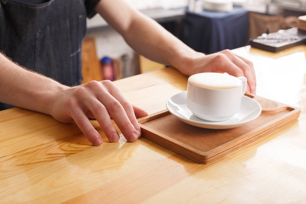 Barman serving coffee cup on wooden bar counter - Foto, immagini