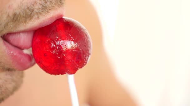 sexy man eten een lolly. simulatie van orale seks. tong likken snoep, 4k, slow-motion. kopie ruimte - Video