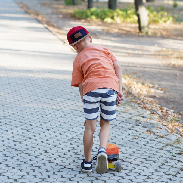 Városi kisfiú egy penny gördeszka. Gyerek korcsolyázás a nyár. - Fotó, kép