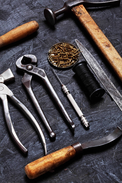 Set of cobbler vintage tools pliers, nippers, hook sewing, cobbler's hammer on the dark wooden background. Top view - Foto, afbeelding