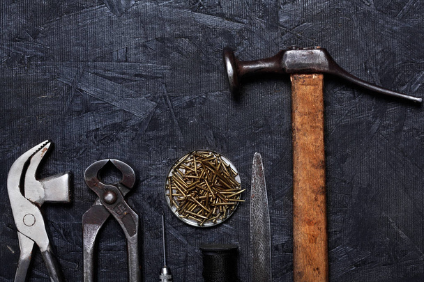 Set of cobbler vintage tools pliers nippers hook sewing cobbler's hammer on the dark wooden background. Top view.Copy space - Fotó, kép