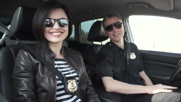 Dwóch policjantów uśmiechający się siedzi w samochodzie - Materiał filmowy, wideo