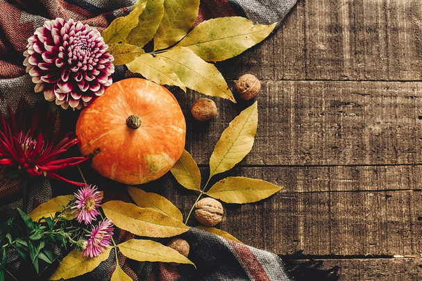 Herbstkürbis mit Blättern und Walnüssen und Dahlien auf stilvollem  - Foto, Bild