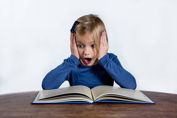 shocked little girl with a book on a white background - Foto, Imagen