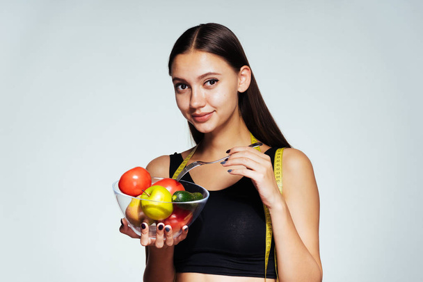 uma jovem observa sua figura e segura em suas mãos maçãs úteis, quer perder peso e se tornar magro
 - Foto, Imagem