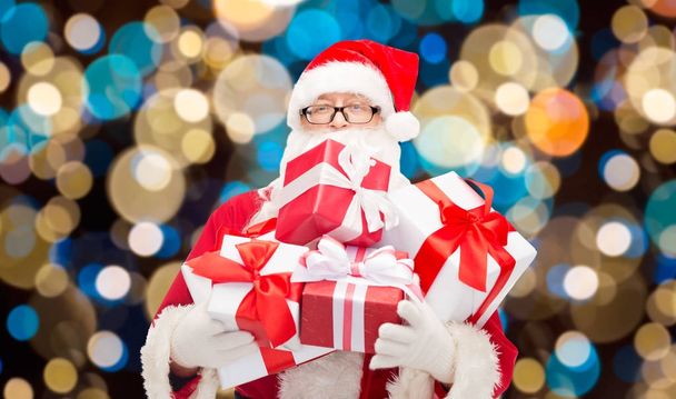 santa claus with christmas gifts over lights - Photo, image