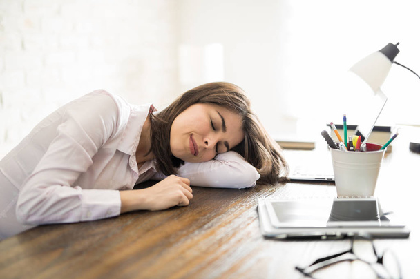 Mujer cansada durmiendo en su escritorio
 - Foto, imagen