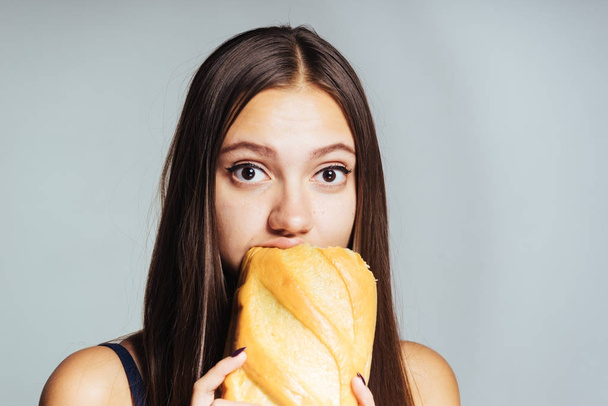 a hungry girl is on a diet, eagerly eats harmful white bread - Foto, imagen