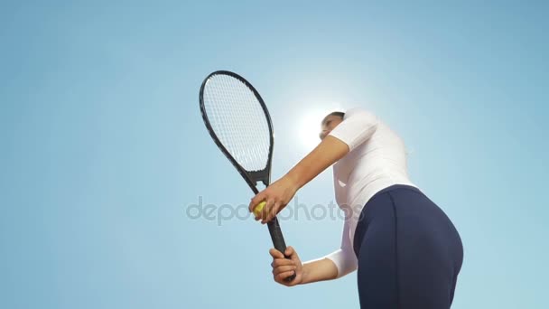 Beautiful young girl tennis player woman serving ball with racket outdoor with sun behind her - Imágenes, Vídeo