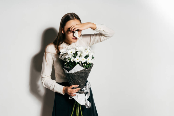 the girl holds a large bouquet of white flowers and sneezes because she has an allergy - Фото, зображення