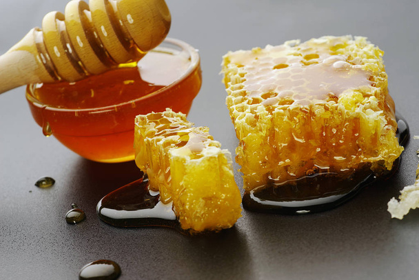 Honing en honingraat op een zwarte achtergrond - Foto, afbeelding