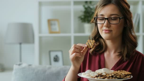 woman in glasses eat cookies - Filmati, video