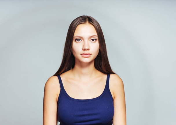 young beautiful girl in blue top posing against white wall background - Photo, Image