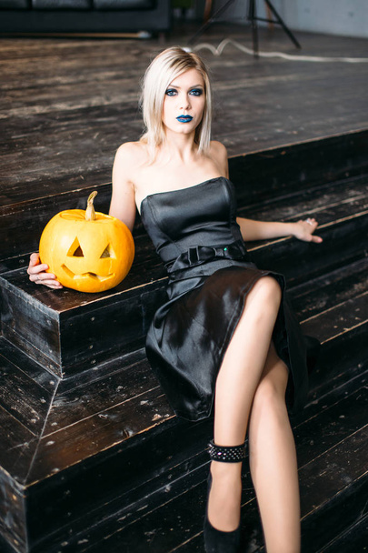 Young blonde woman holding pumpkins for halloween - Foto, afbeelding