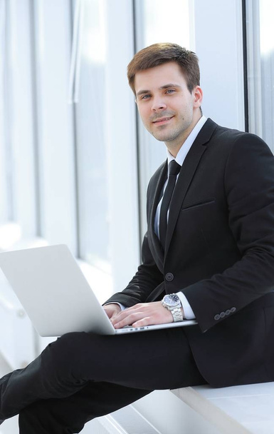 young professional with laptop on background of office window - Foto, afbeelding