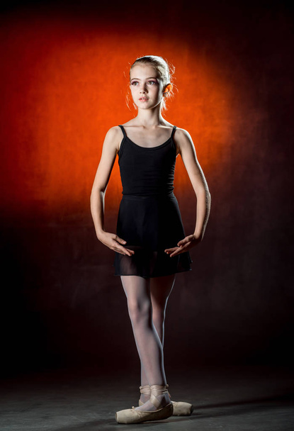 Ballerina. Cute little girl posing and dancing in studio. The girl is studying ballet. Dark background. - Fotó, kép