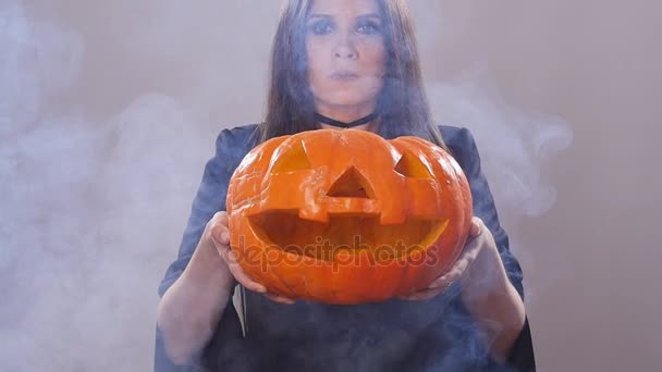 Γυναίκα στέκεται με την κολοκύθα σε καπνό - Πλάνα, βίντεο