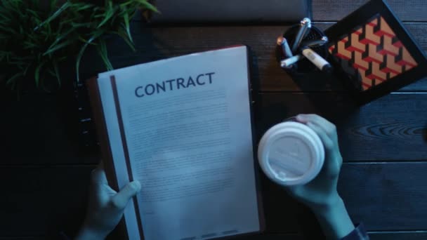 Overhead shot of man reading contract with cup of coffee in his hand - Felvétel, videó