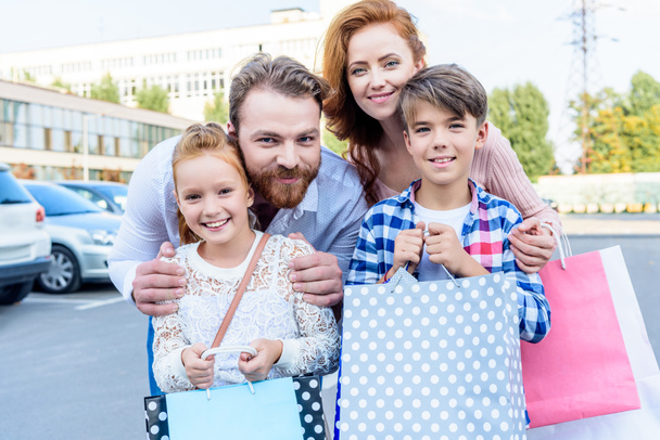 parents hugging children with shopping bags - Photo, Image