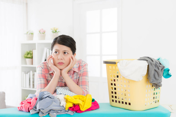 unhappy attractive woman maid folding clothes - 写真・画像