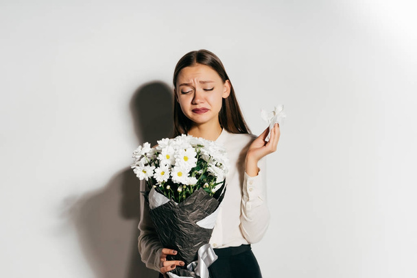 a young upset girl sneezes because she is allergic to flowers - Zdjęcie, obraz