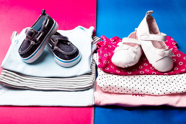 Folded blue and pink bodysuit with boat shoes on it on minimalistic pink and blue background. diaper for newborn boy and girl. Stack of infant clothing. Child outfit - Fotoğraf, Görsel