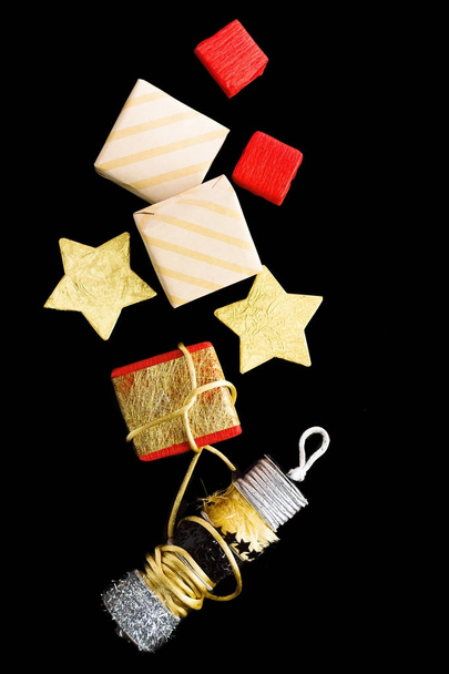 Flat lay Regalos de Navidad rojos, dorados y beige con cintas y estrellas de aluminio sobre fondo negro
 - Foto, Imagen