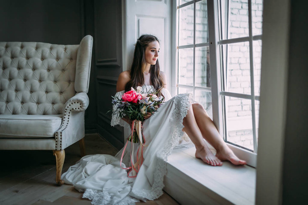 Woman by the window. Bride looking out the window, she waits for the groom. - Zdjęcie, obraz