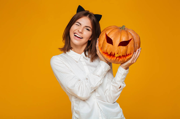Cute teenage schoolgirl in uniform holding halloween pumpkin - Photo, image
