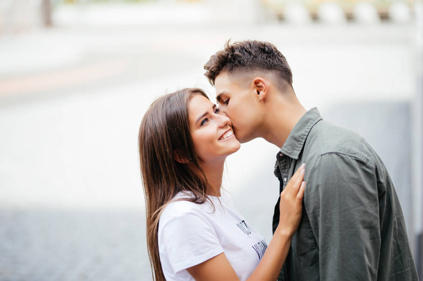 красивий молодий чоловік цілує щоку своєї коханої на вулиці
 - Фото, зображення
