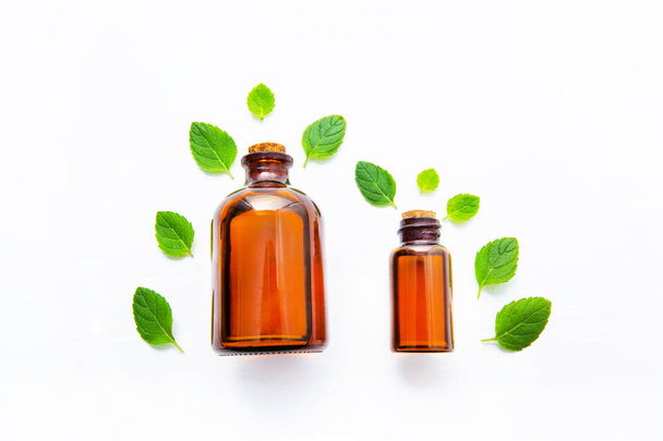 Natural Mint Essential Oil in a Glass Bottle with Fresh Mint Leaves on white over wooden background. - Φωτογραφία, εικόνα