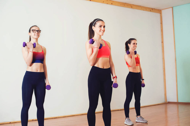 Gruppe junger Frauen in Sportbekleidung mit Kurzhanteln beim Training im Fitnessstudio. - Foto, Bild