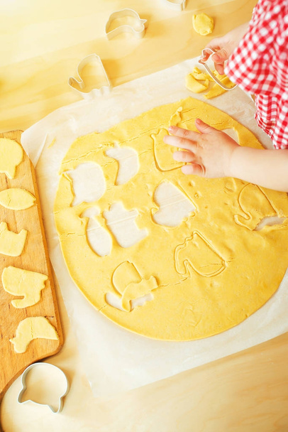 Kid's hands cut cookie from raw dough , top view. - Фото, зображення